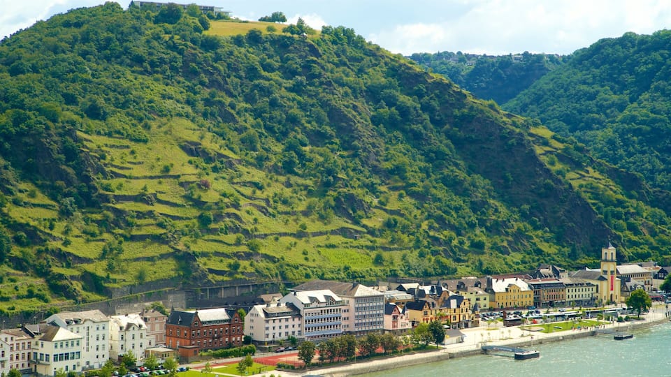 A town with a river, buildings, and a hill with greenery.