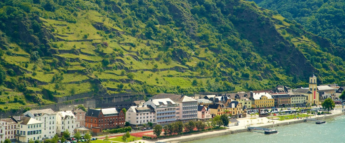 A town with a river, buildings, and a hill with greenery.