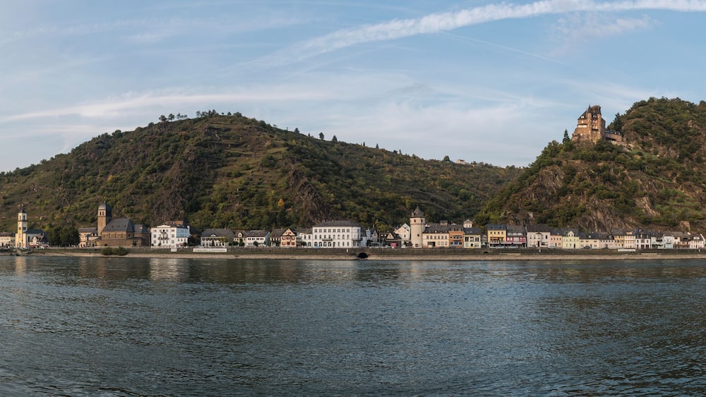 Une rivière traversée par un pont, une ville construite sur une colline et un château.
