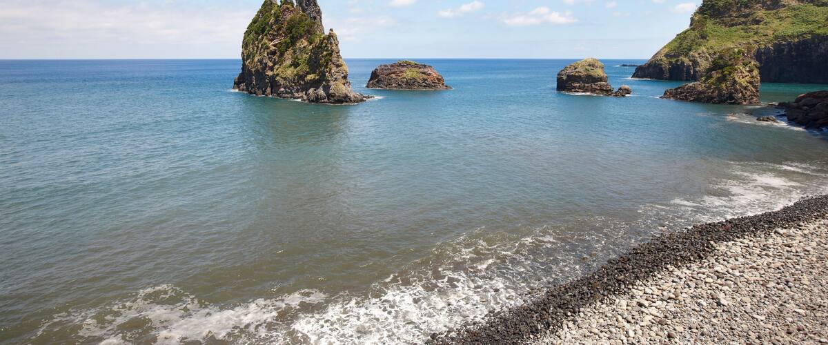 A coastal landscape with rocky formations and calm sea.