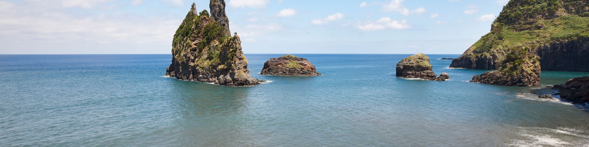 A coastal landscape with rocky formations and calm sea.