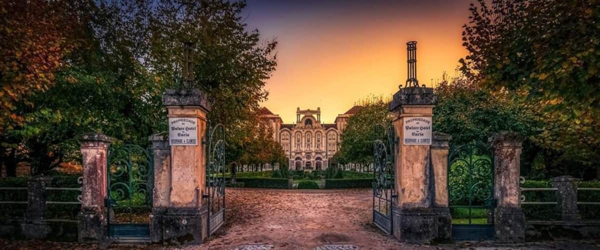 A historic building with ornate architecture, surrounded by a cobblestone pathway and iron gates.