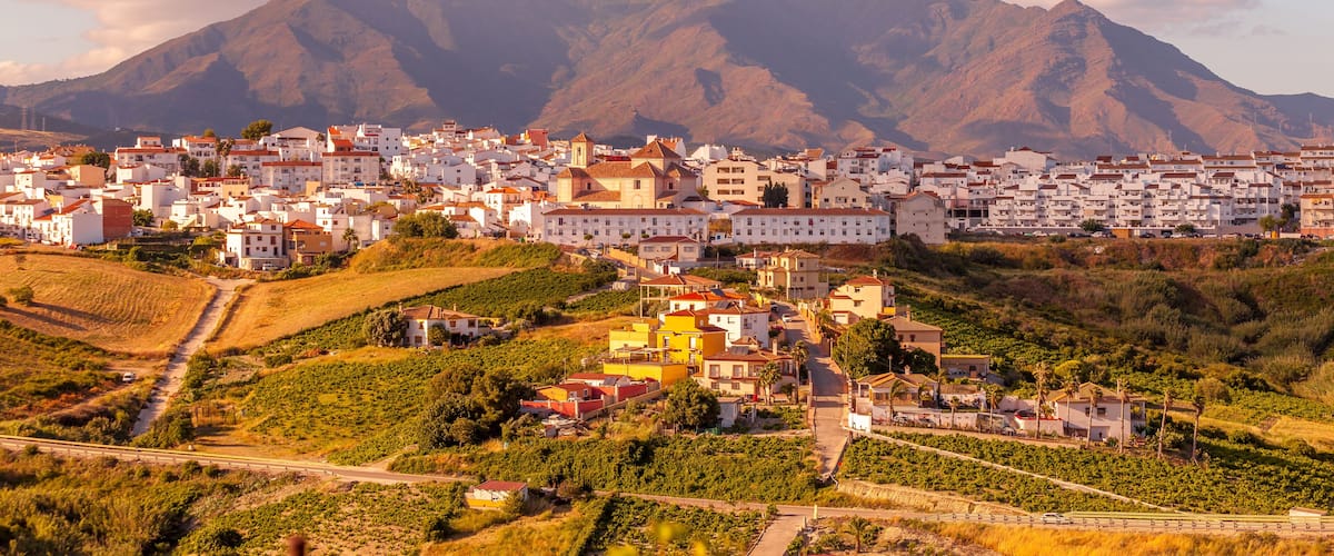 Un pueblo situado en un valle, con una cadena montañosa al fondo.
