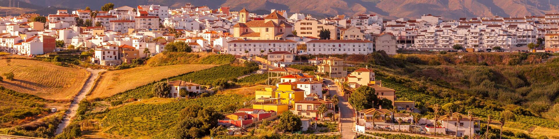 A town nestled in a valley with a mountain range in the background.