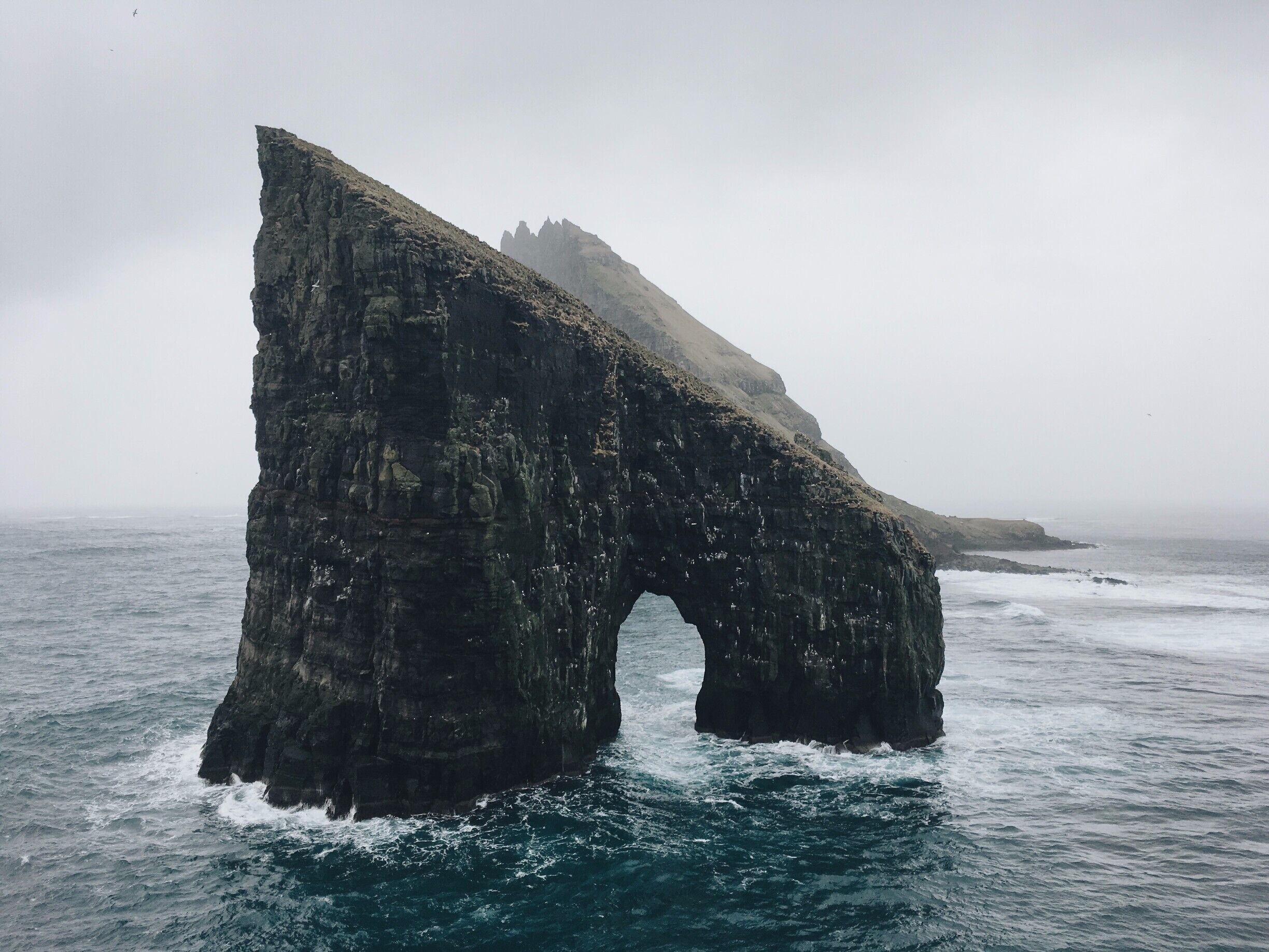 A little off-track route towards an fantastic rock in the ocean surrounded by massive cliffs and a steep island behind it.
The scenery is just stunning for photography or just be blown away its beauty (and the winds). Be carefull with the steep cliffs.

On the hike back we were followed all the time by a cute seal.
 #hiking #nature #faroeislands #drangarnir #vikings #earth #places

Feel free to follow my travels on:
https://www.facebook.com/ShotByCanipel/
https://www.instagram.com/canipel/