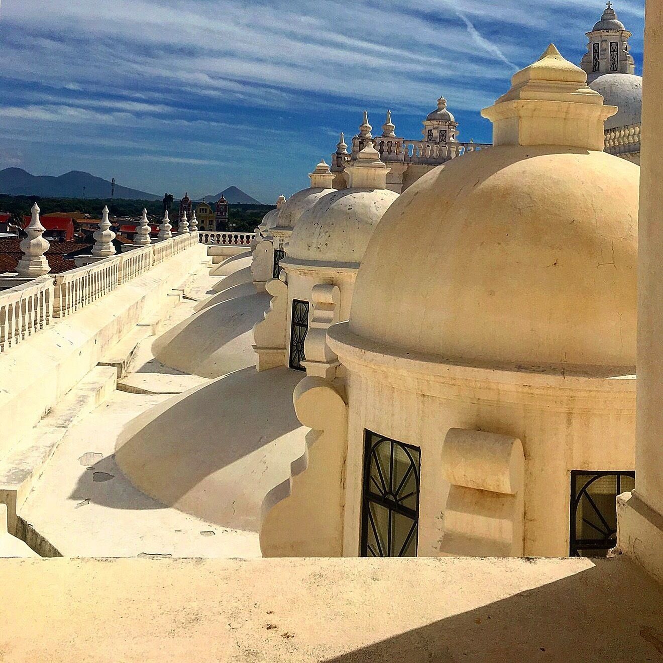 A domed building with a balcony and a mountain in the background.