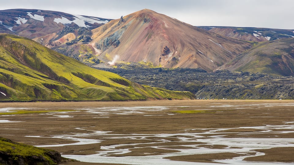 A mountainous landscape with green slopes and a glacier.