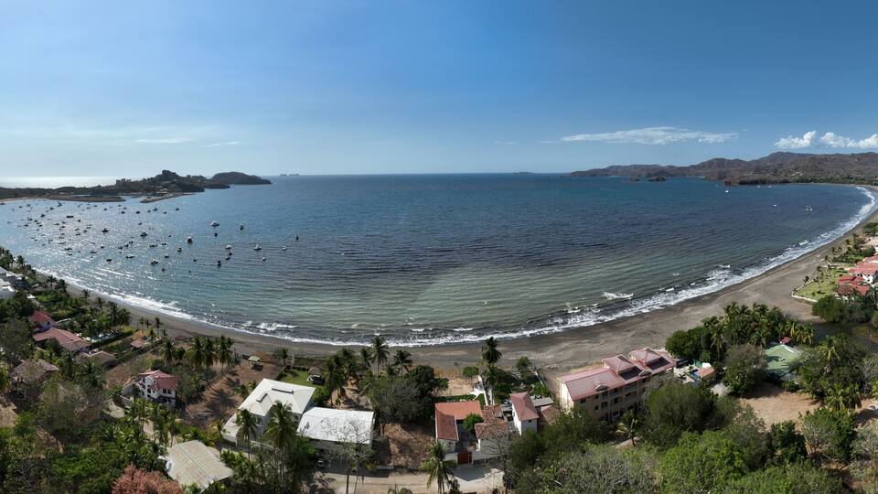 Une ville côtière avec une plage, des bateaux et, en arrière-plan, une chaîne de montagnes.