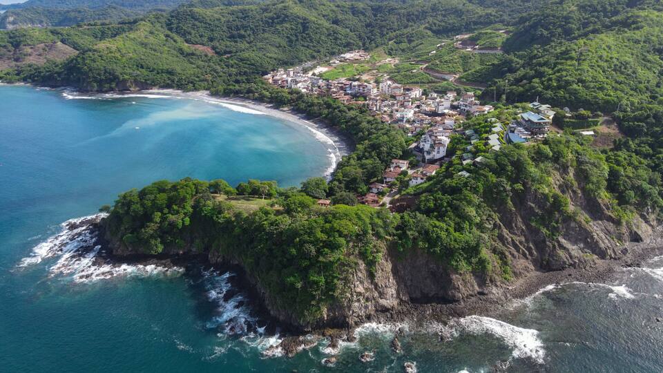 Une ville côtière nichée entre de verdoyantes collines et une baie aux eaux turquoise.