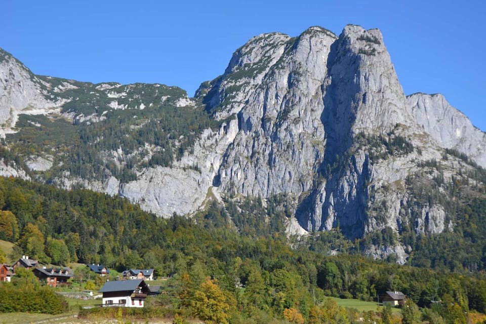 Un paisaje montañoso con un pico rocoso destacado y un pueblo a su base.