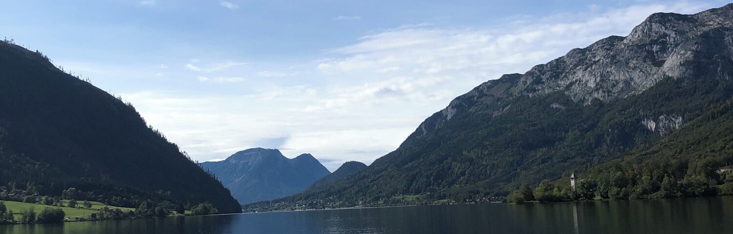 A calm lake surrounded by mountains and a clear sky.