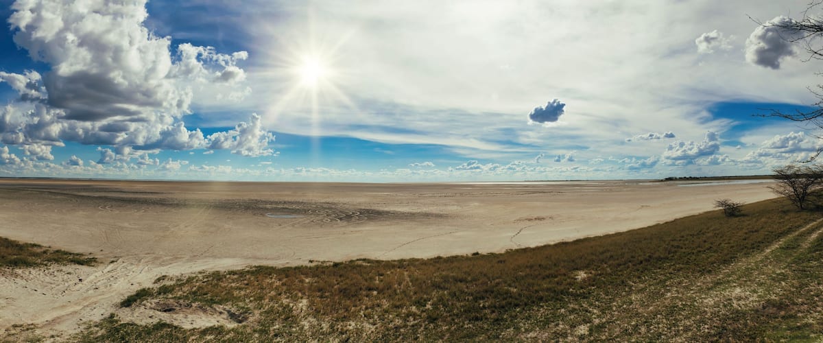 A vast, flat landscape with sparse vegetation and a clear sky with scattered clouds.
