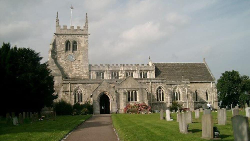 Eine historische Kirche mit hohem Turm und einem Friedhof.