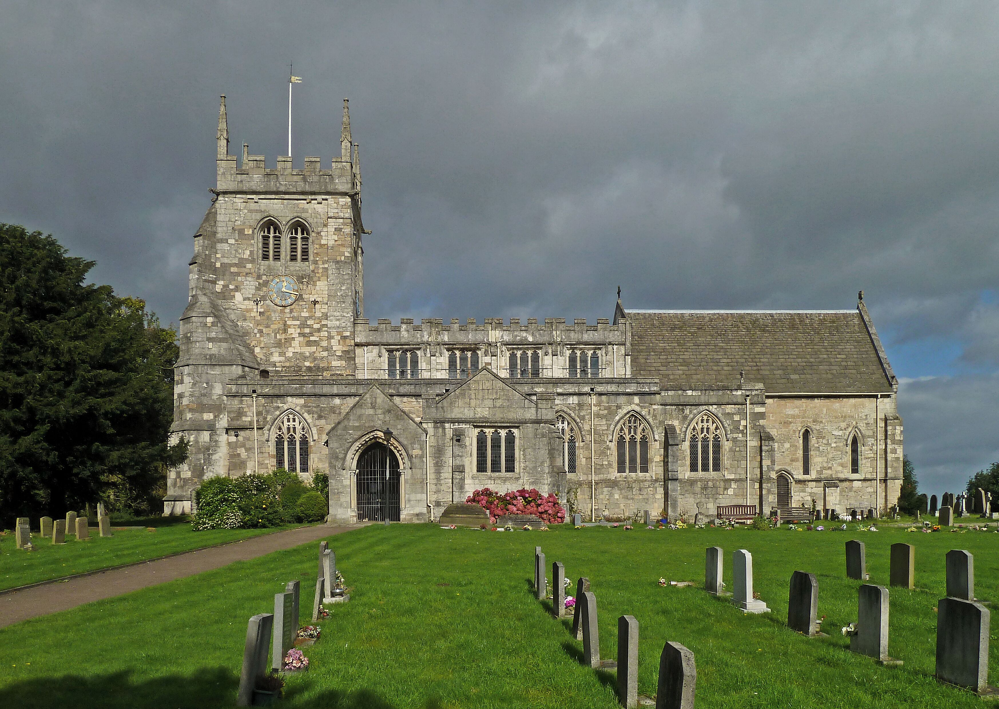 A historic church with a tall tower and a graveyard in front.