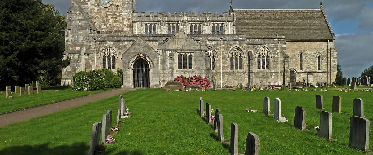 A historic church with a tall tower and a graveyard in front.