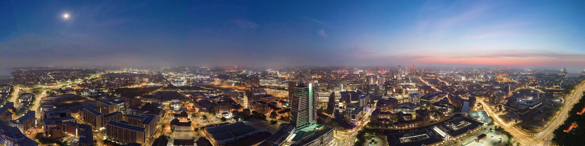 A cityscape at night with illuminated buildings and a clear sky.