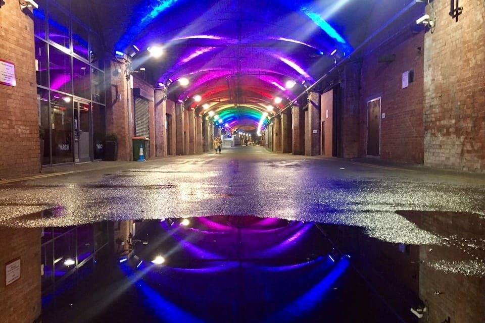 A wet street with colorful lights reflecting on the surface.