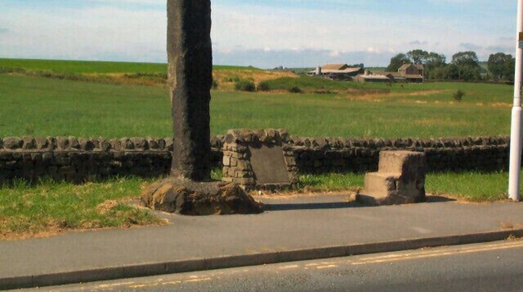 Long Stoop. At the western side of the main Airport roundabout of the A658. The accompanying stone inscription reads: 'THIS MARKER STONE (LONG STOOP) ERECTED HUNDREDS OF YEARS AGO TO GUIDE TRAVELLERS TOWARDS AN ANCIENT SETTLEMENT AT DENE HEAD TO THE EAST WAS MOVED FROM ITS EARLIER SITE 186 YARDS TO THE SOUTH WEST IN THE YEAR 1984 FOR RUNWAY EXTENSIONS. AIREBOROUGH CIVIC SOCIETY.'
