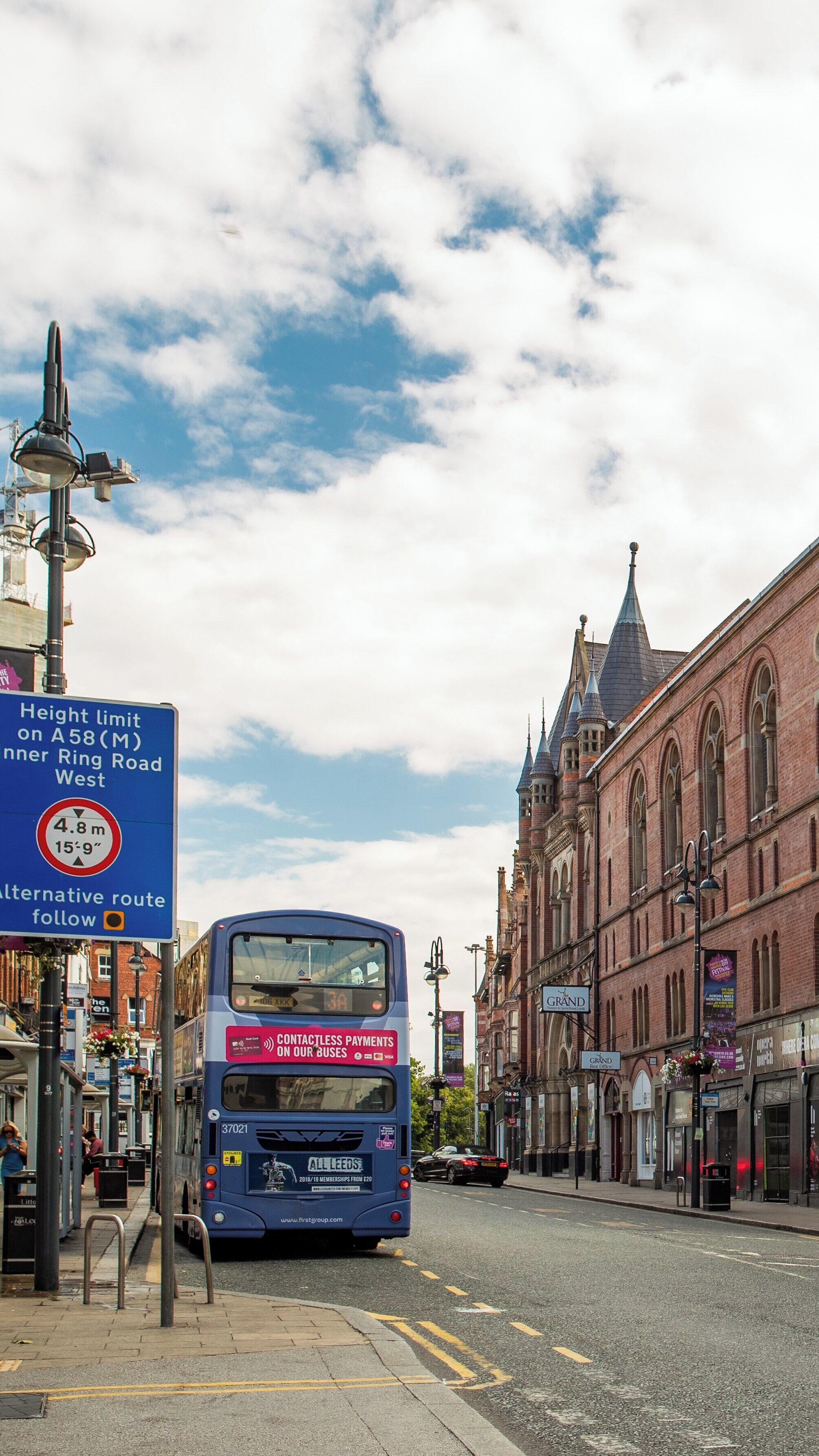 Leeds Grand Theatre showcases vibrant architecture in Leeds City Center with a busy bus stop nearby under blue skies