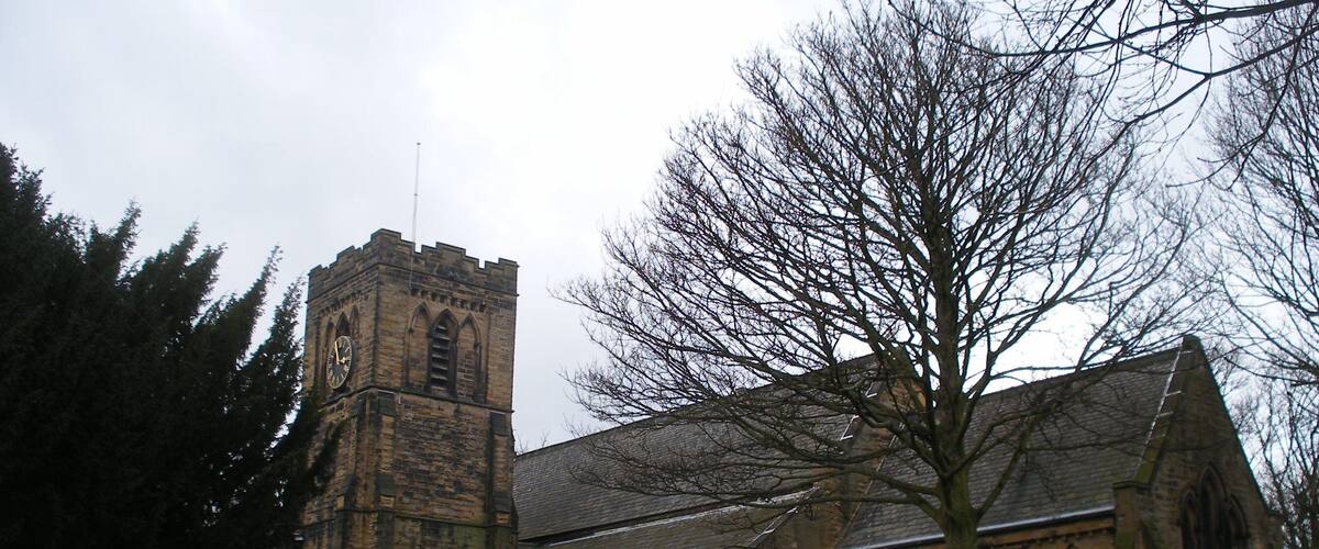 A church with a clock tower and a cemetery with headstones.