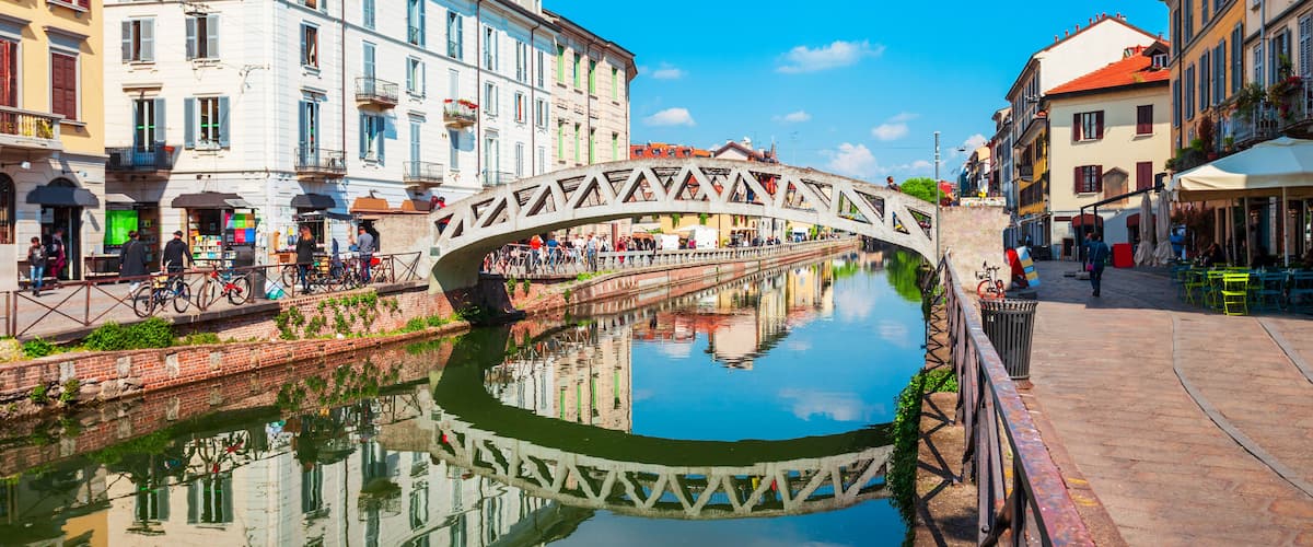 A pedestrian bridge over a canal with buildings on either side.
