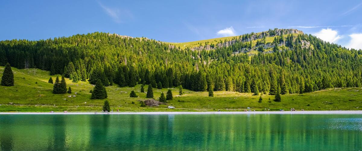 A lake surrounded by forested hills and a clear sky.