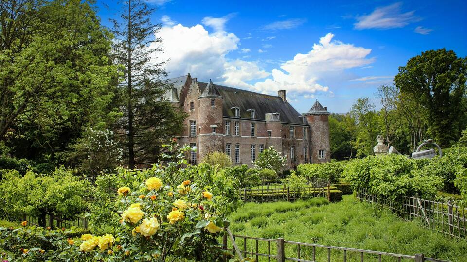 A historic castle surrounded by lush greenery and blooming yellow roses.
