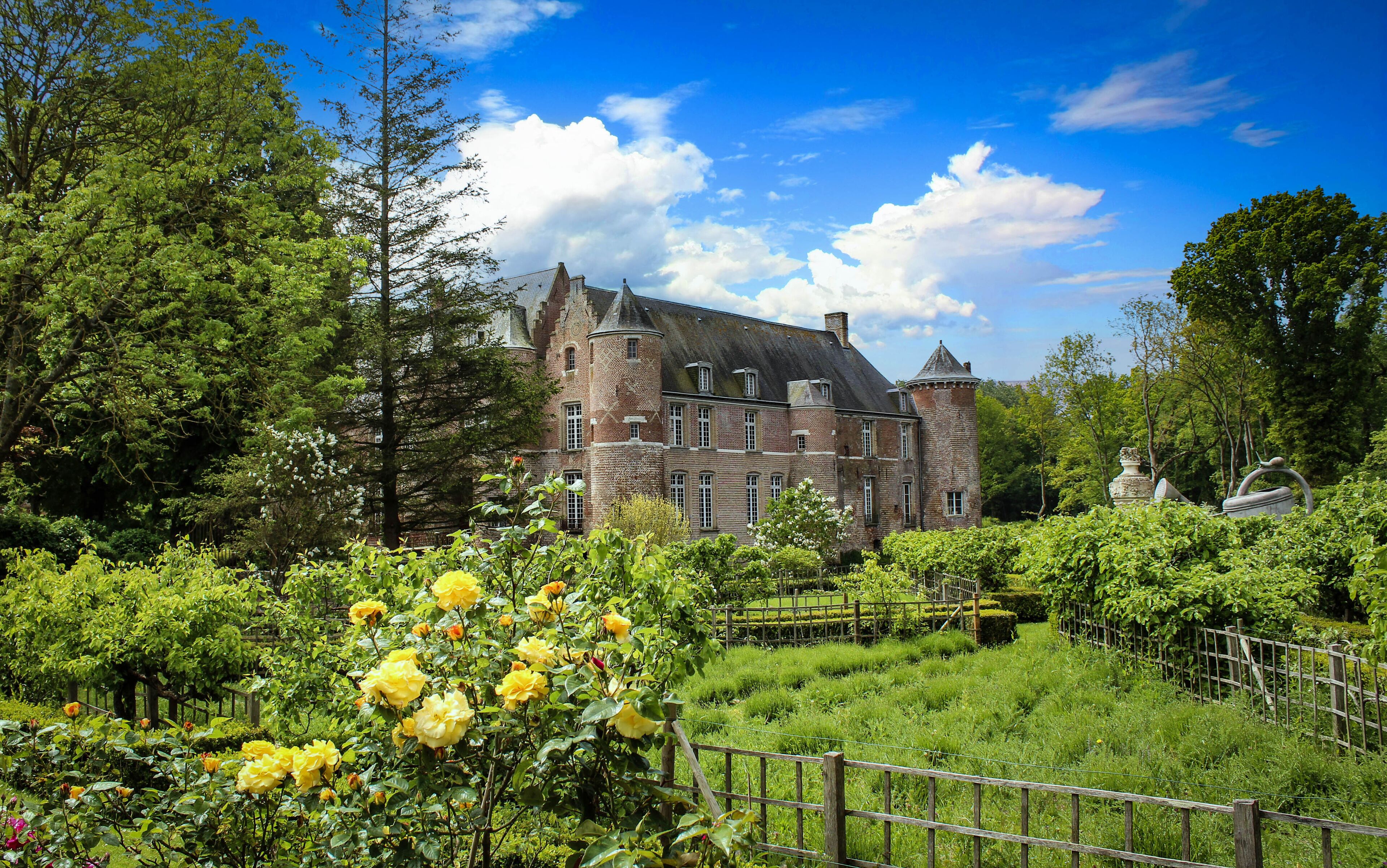 A historic castle surrounded by lush greenery and blooming yellow roses.
