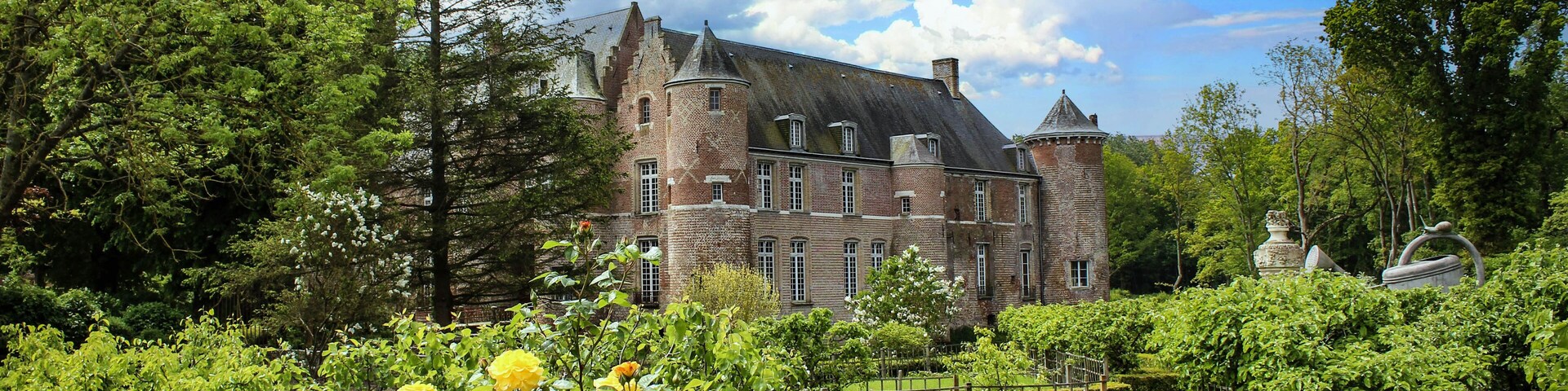 A historic castle surrounded by lush greenery and blooming yellow roses.