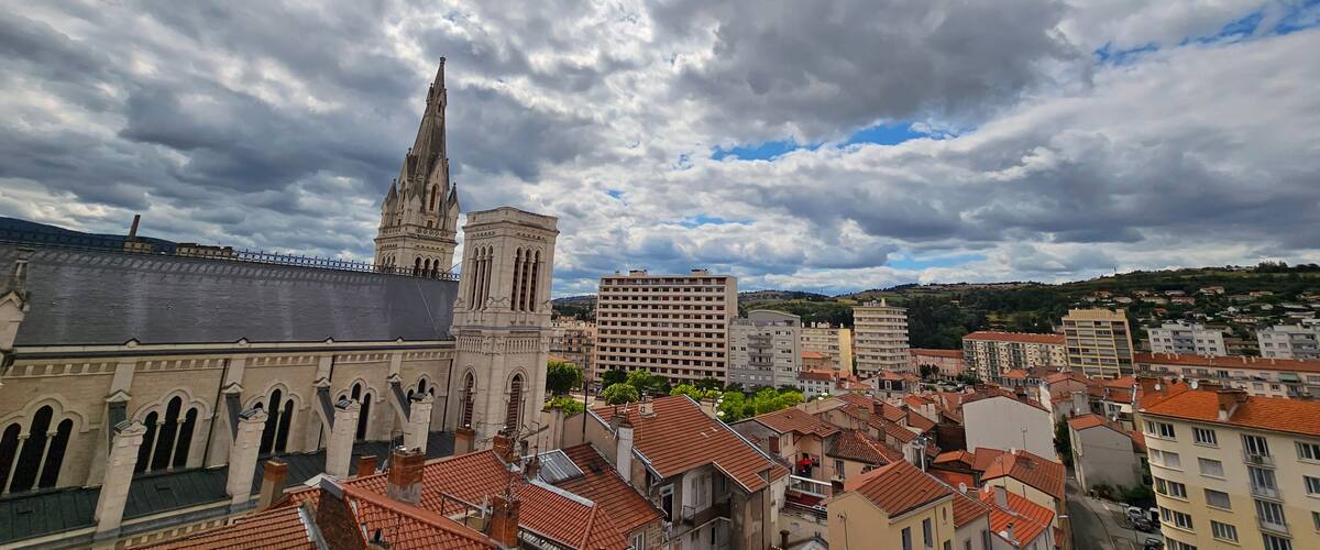 A cityscape with historic architecture, including a prominent church with a tall spire and a large building with a flat roof.