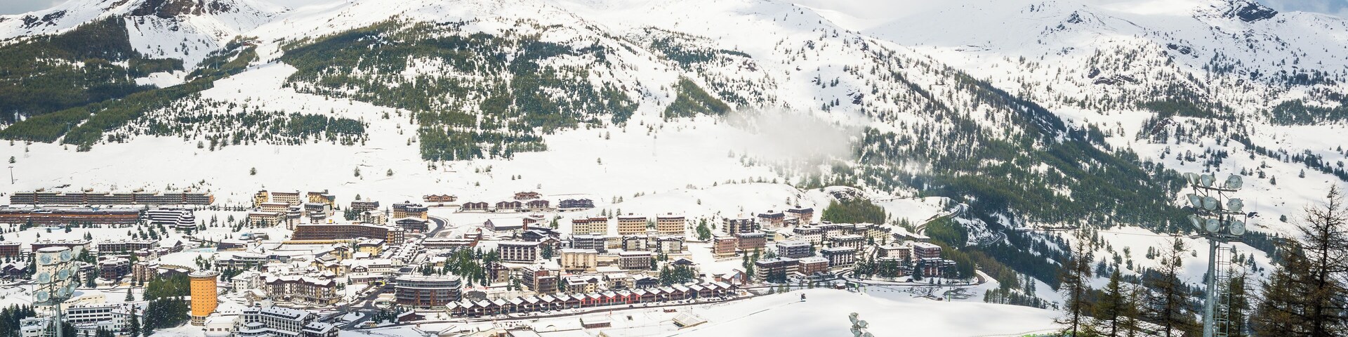 A snow-covered mountain town with buildings, ski slopes, and a lake.