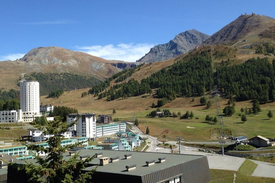 A mountainous landscape with a modern building complex and a tall tower.