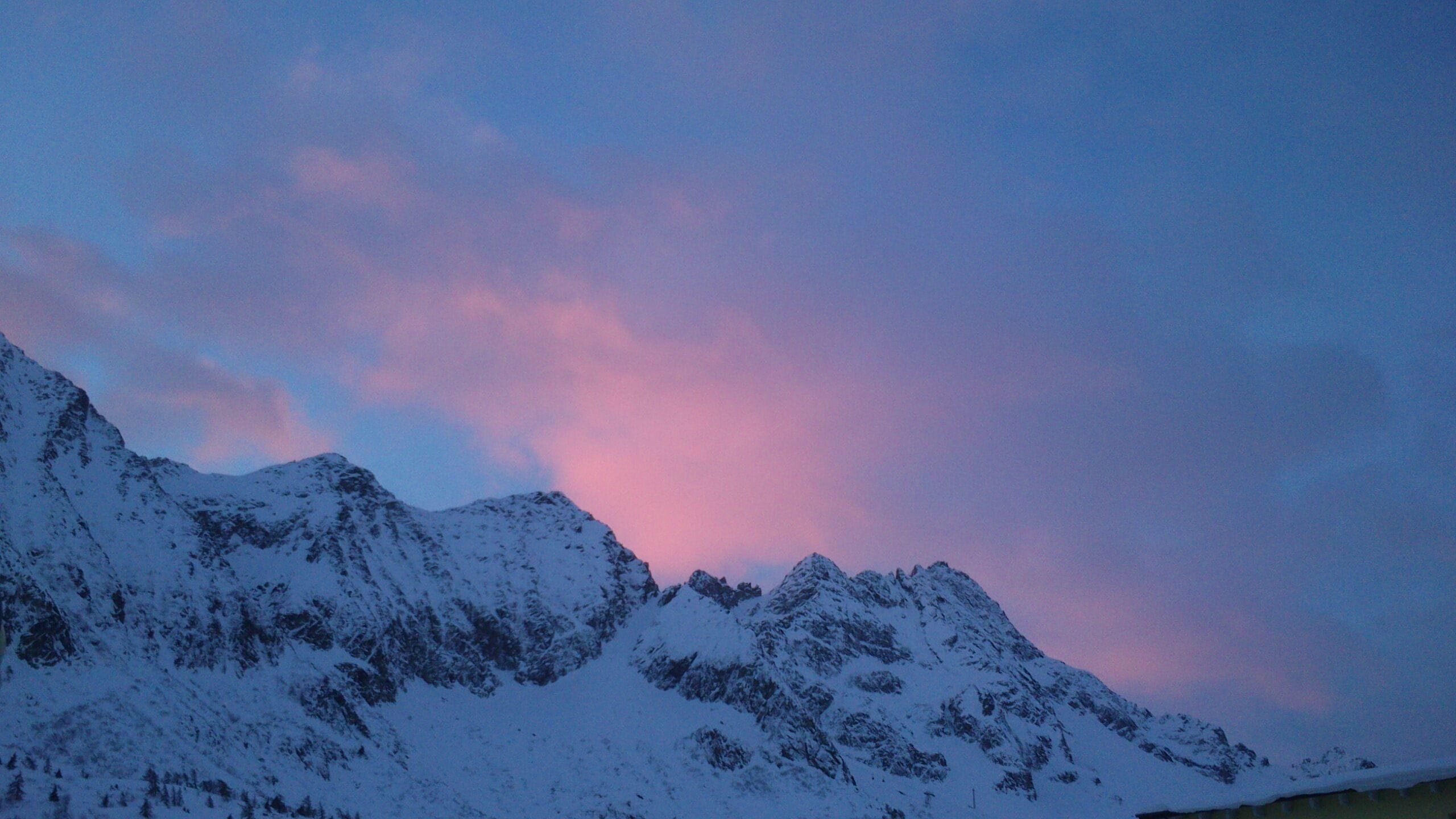 Snow-covered mountains under a pink and blue sky.