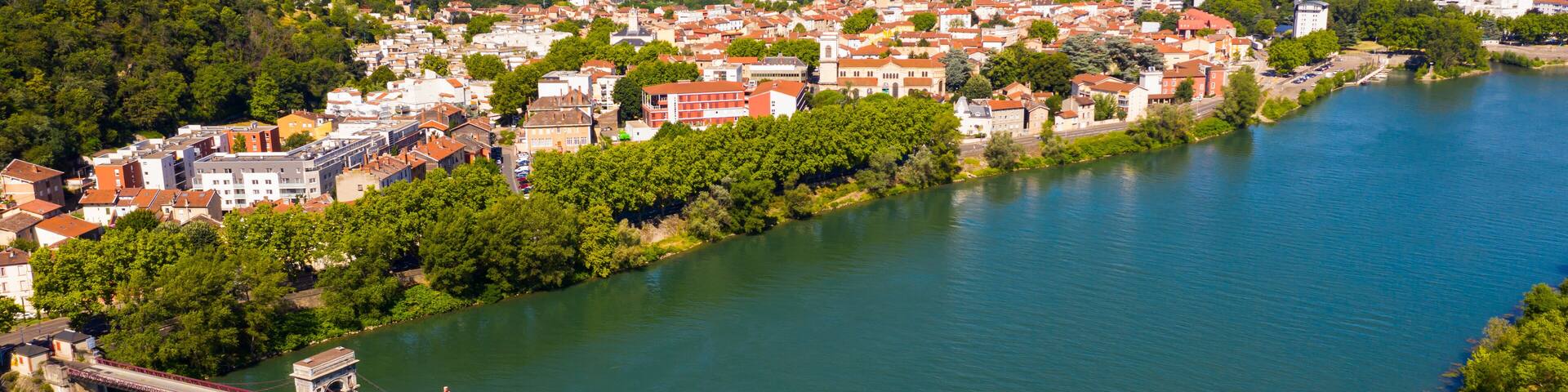 A river with a bridge, surrounded by greenery and buildings.