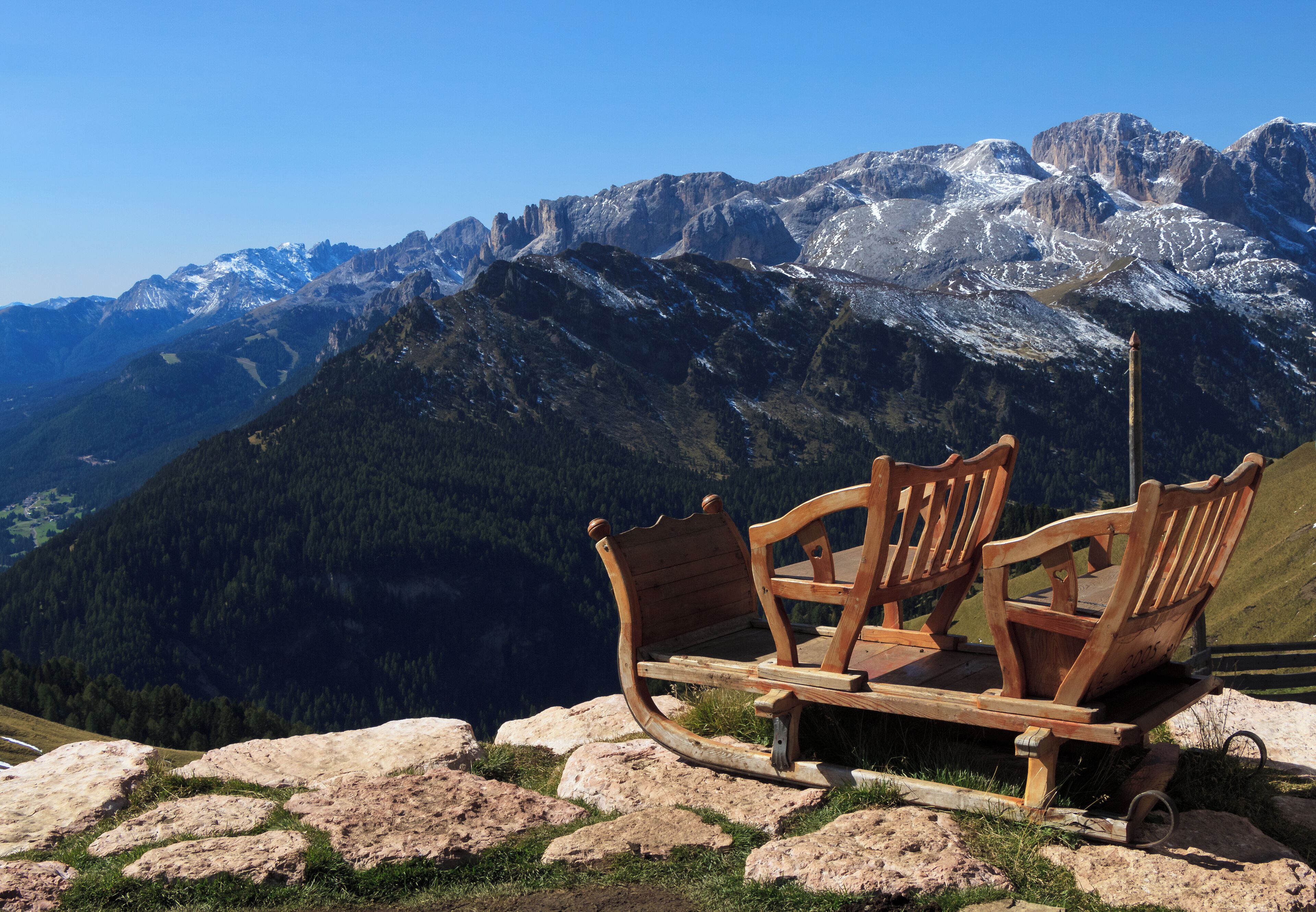 A wooden bench overlooking a mountainous landscape with snow-capped peaks.