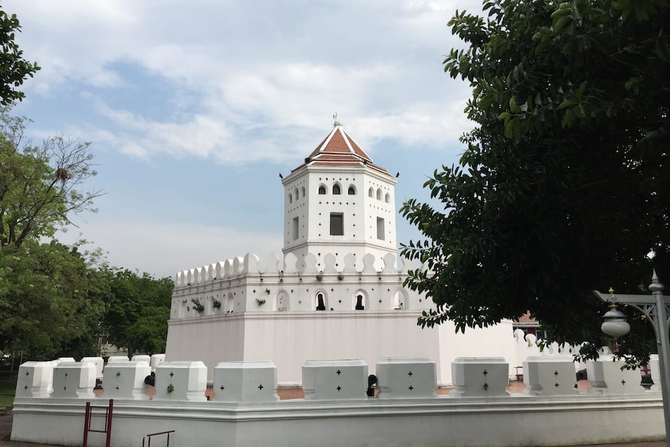Een witte kerk met een klokkentoren en kruisbeelden op de gevel.