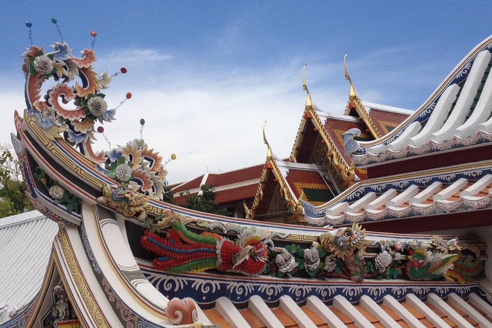 Et traditionelt thai tempel med detaljerede udsmykninger og en klar blå himmel.
