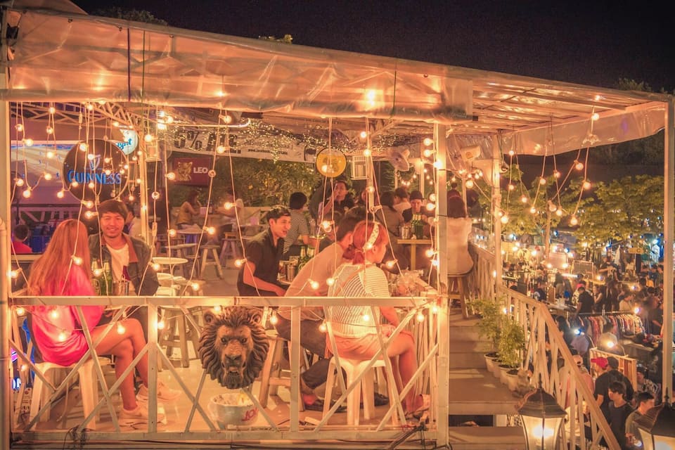 A covered outdoor market with string lights and a lion statue.