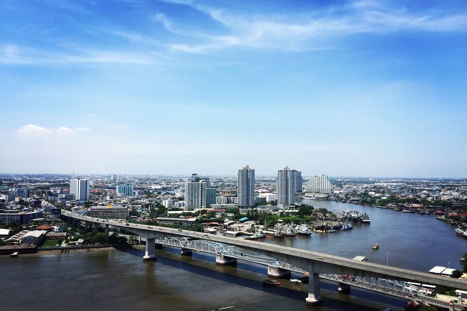 A river with a bridge, a cityscape with high-rise buildings, and a clear sky.