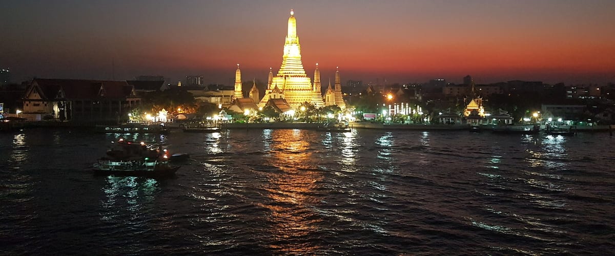 A romantic evening in Bangkok; with a view across the Chao Phraya River to Wat Arun, or Temple of Dawn. A number of trendy bars have opened on the top floors of old shophouses not far from famous Wat Pho temple.
