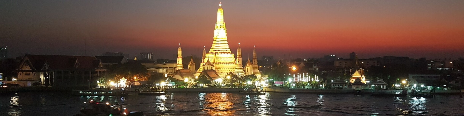 A romantic evening in Bangkok; with a view across the Chao Phraya River to Wat Arun, or Temple of Dawn. A number of trendy bars have opened on the top floors of old shophouses not far from famous Wat Pho temple.