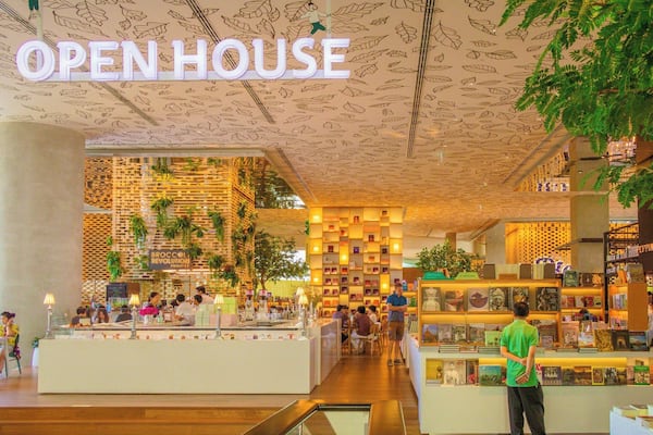 An indoor shopping area with a sign reading "OPEN HOUSE" and various shops and displays.