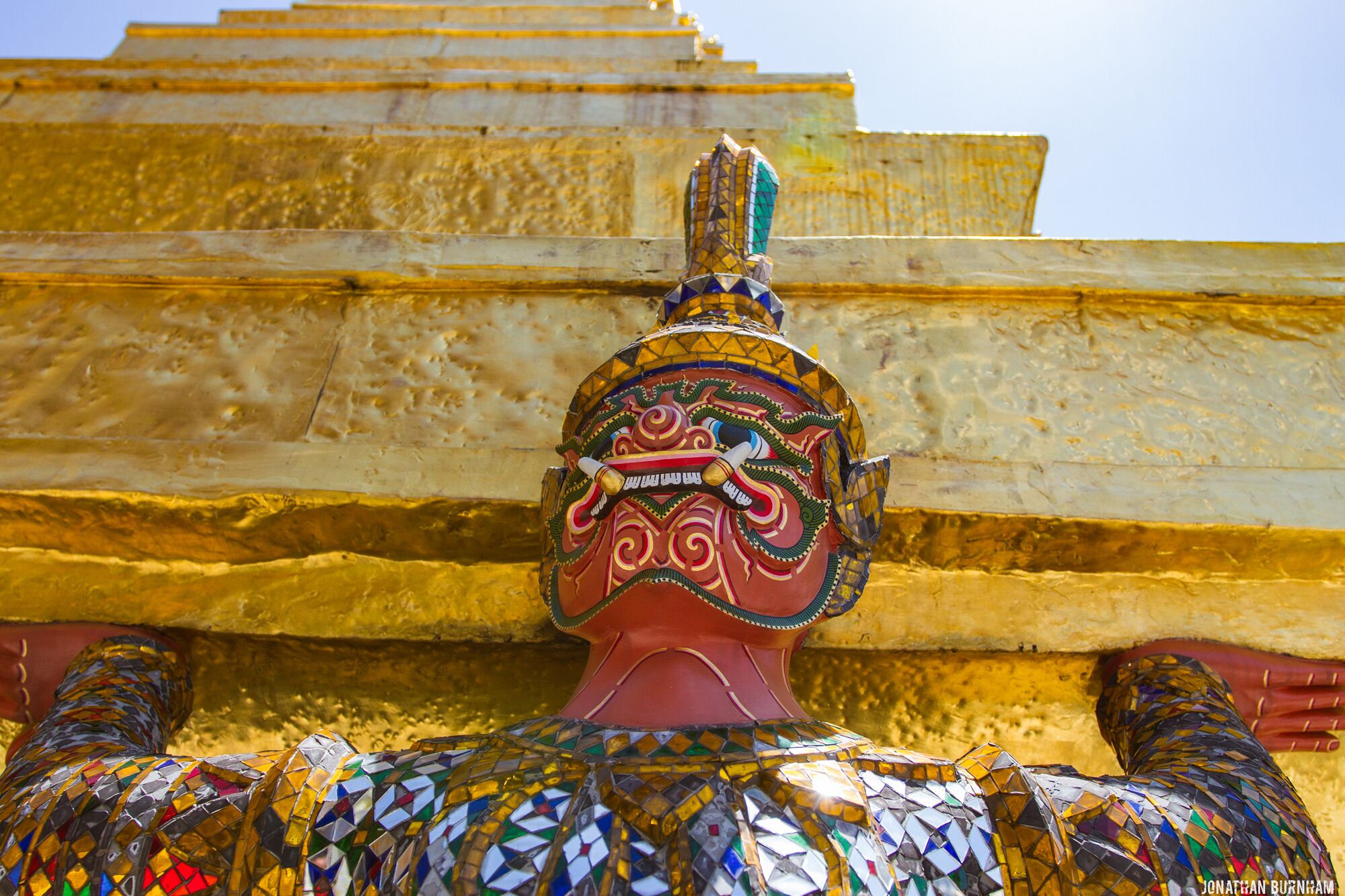 Una estatua colorida y ricamente decorada con un fondo dorado.