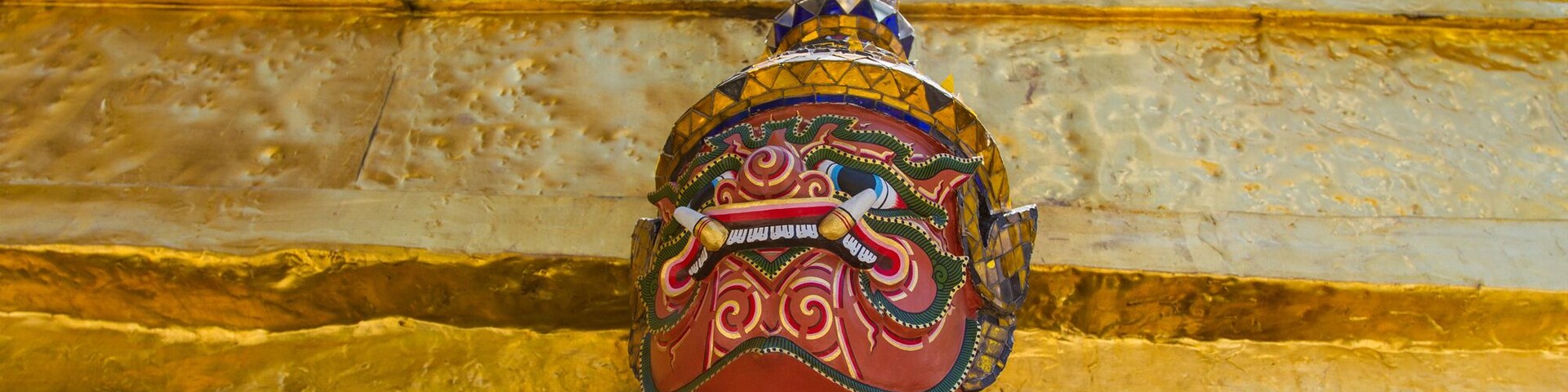 Una estatua colorida y ricamente decorada con un fondo dorado.
