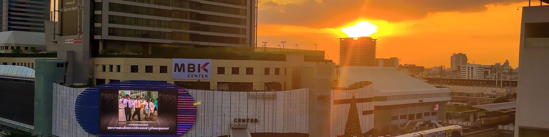 A cityscape with a prominent MBK Center building and a train passing over an elevated track.