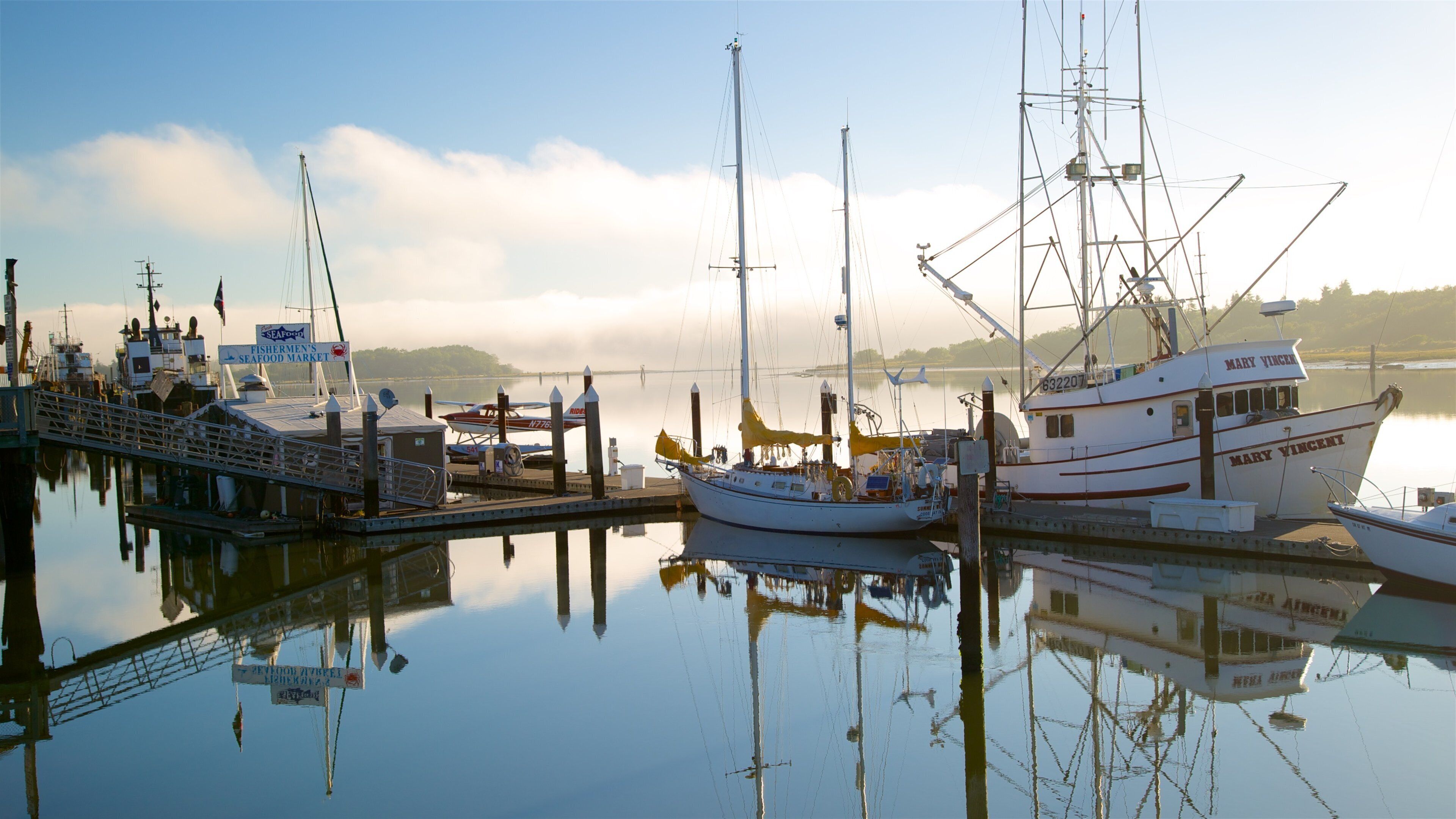 A marina with several boats docked, including a large white boat named 'Mary Vincent' and a smaller plane on the dock.
