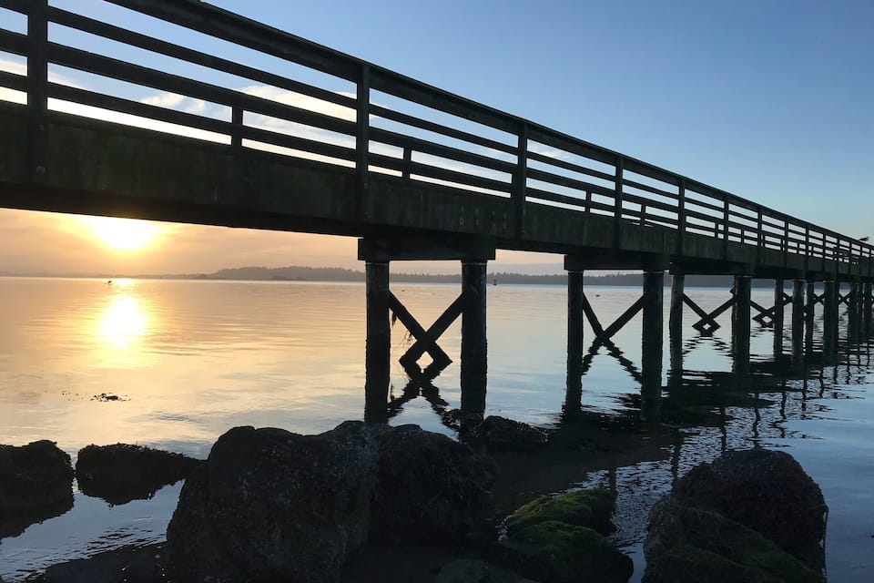 A wooden pier extending over calm water at sunset.