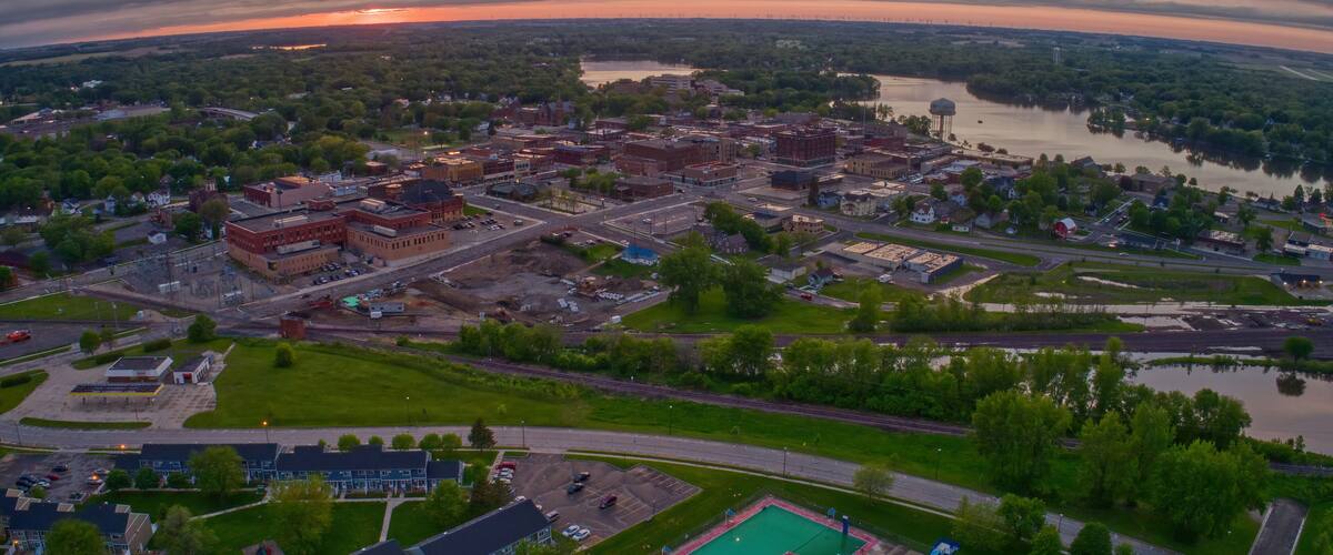 An aerial view of a town with a river, a large building complex, and a swimming pool.