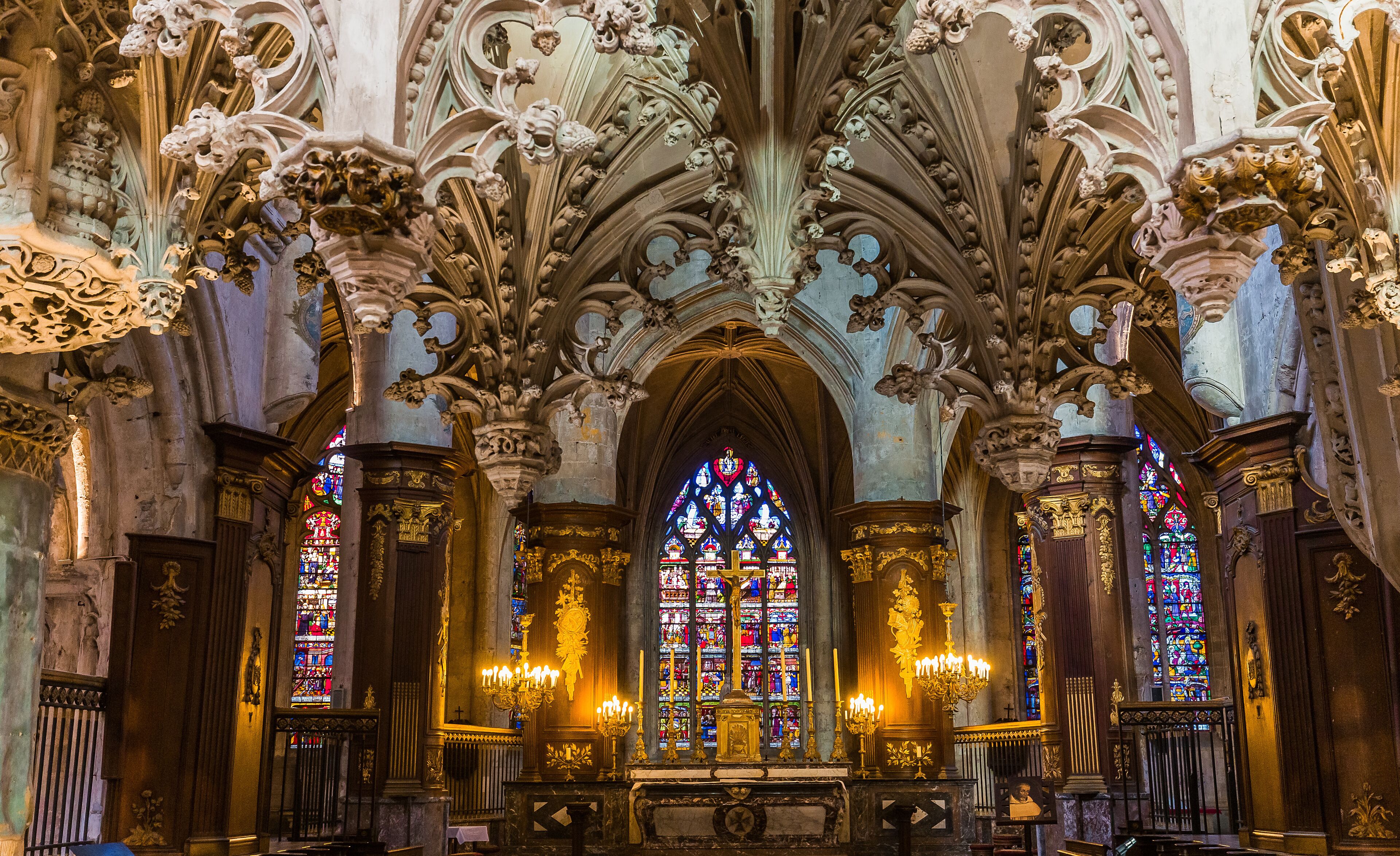 An ornate Gothic church interior with intricate stone carvings, stained glass windows, and a central altar.