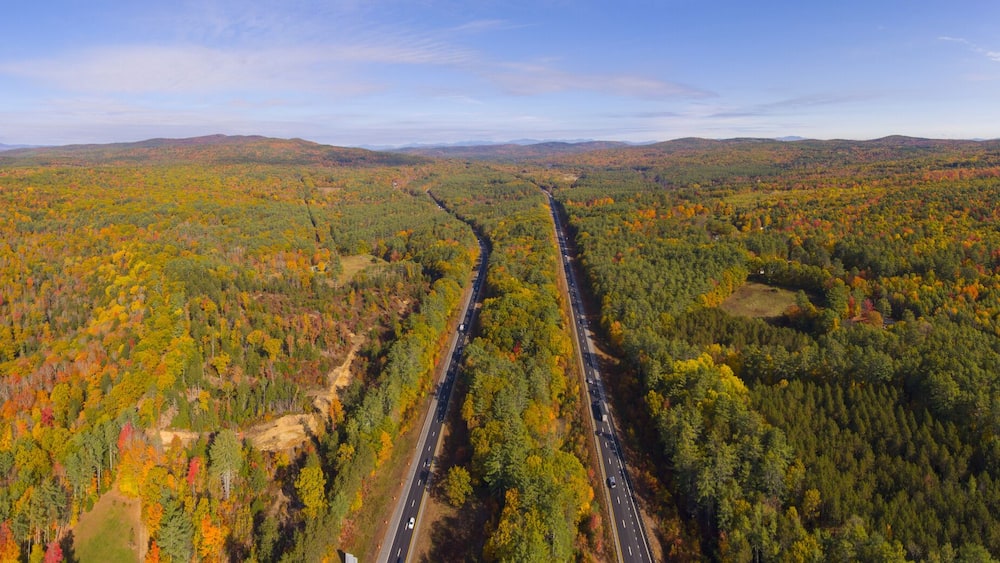 Interstate Highway 93 at Exit 22 with NH Route 127 in White Mountain National Forest panorama aerial view with fall foliage, Town of Sanbornton, New Hampshire NH, USA.